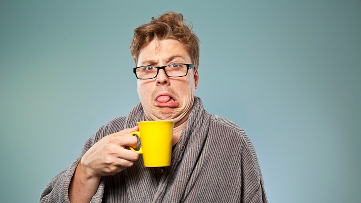 Man pulling a face at a cup of coffee