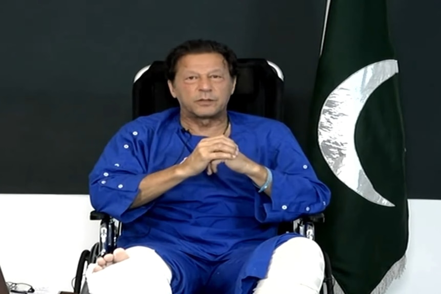 Imran Khan seated with legs in casts as he speaks to cameras.