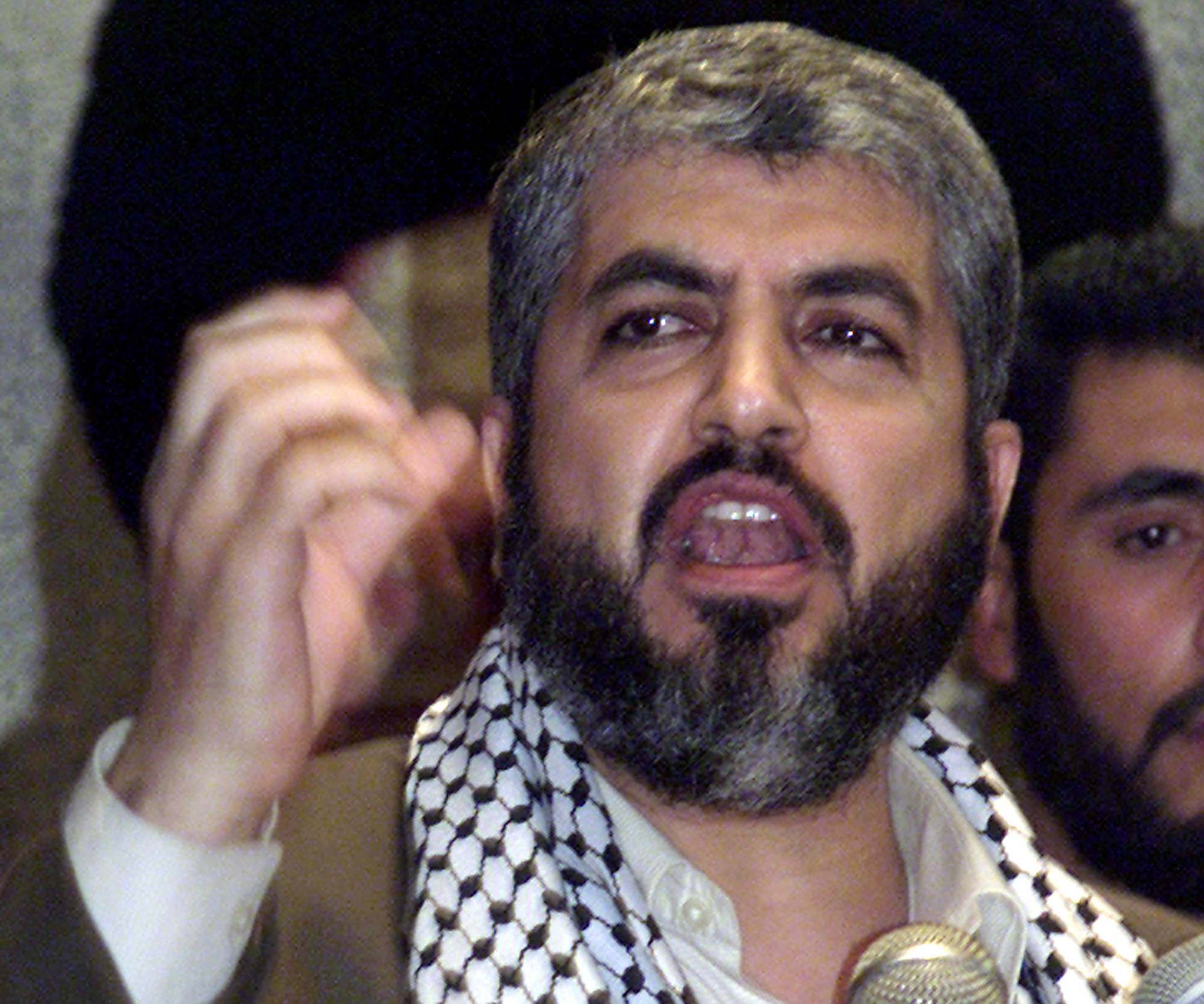 A man with grey hair and dark beard raises his fist while speaking