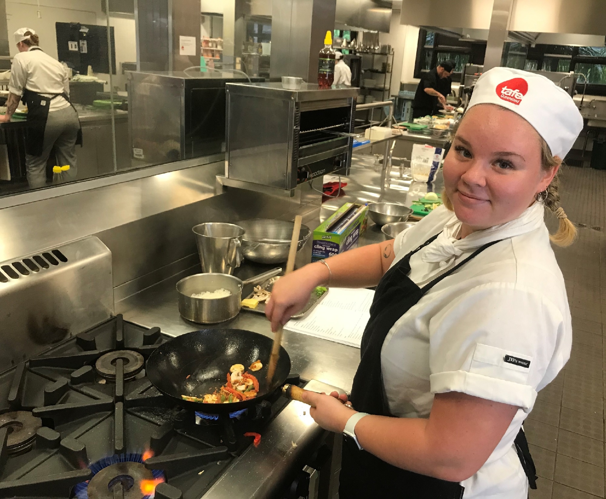 Ashley Groom cooks vegetables in a pan in her chef whites.