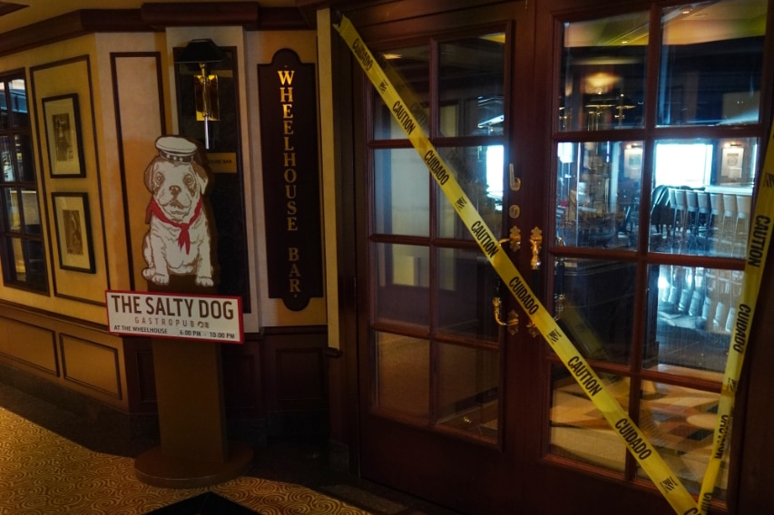 A yellow corden across the entrance to a bar.