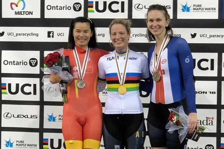 Emily Petricola stands on the podium between two other women after winning a gold medal.