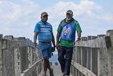 Two men stand on a boardwalk.
