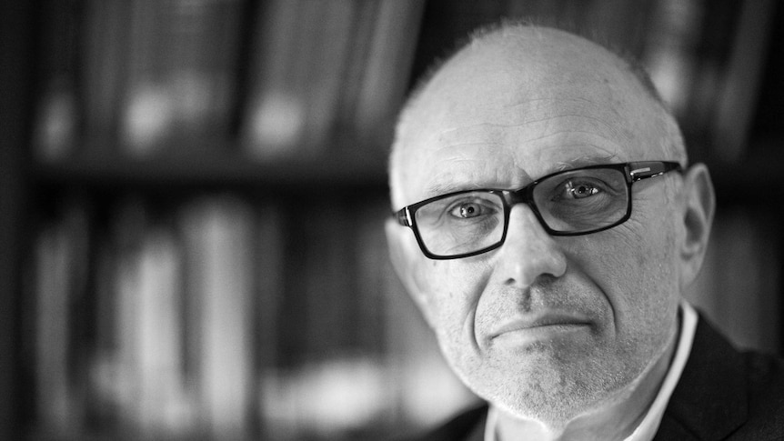 black and white portrait of miroslav volf in suit looking forward with blurred background of bookshelves