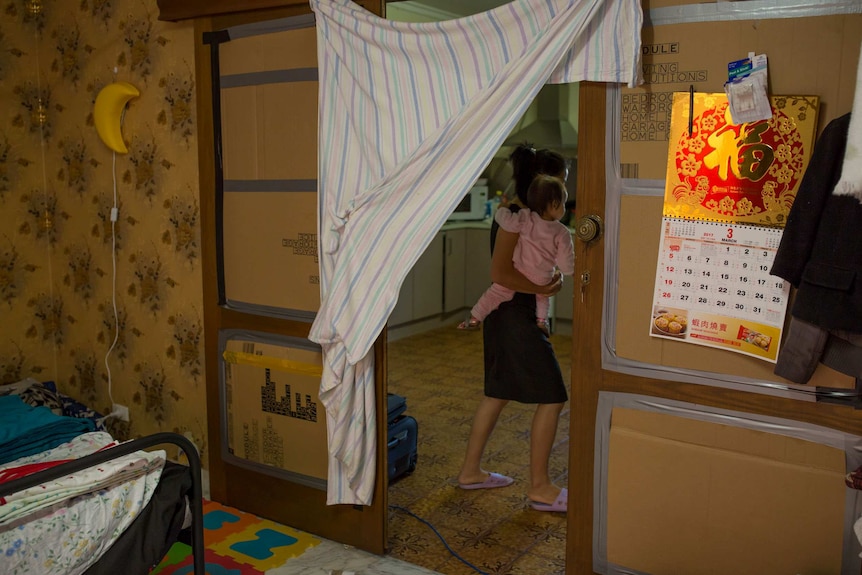 Layla pushes open a curtain made from a sheet hung between cardboard doors.