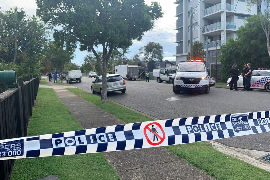 Police tape, vehicles and officers cordon off a street at Wynnum.