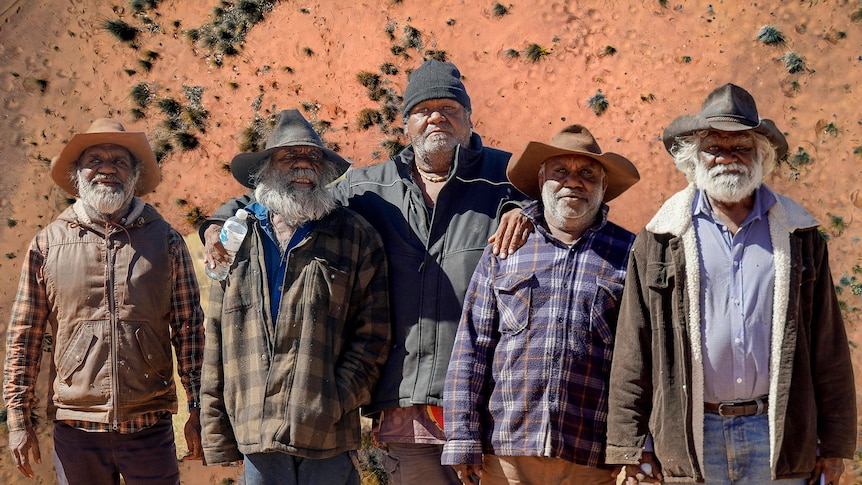 Five indigenous people standing on country.