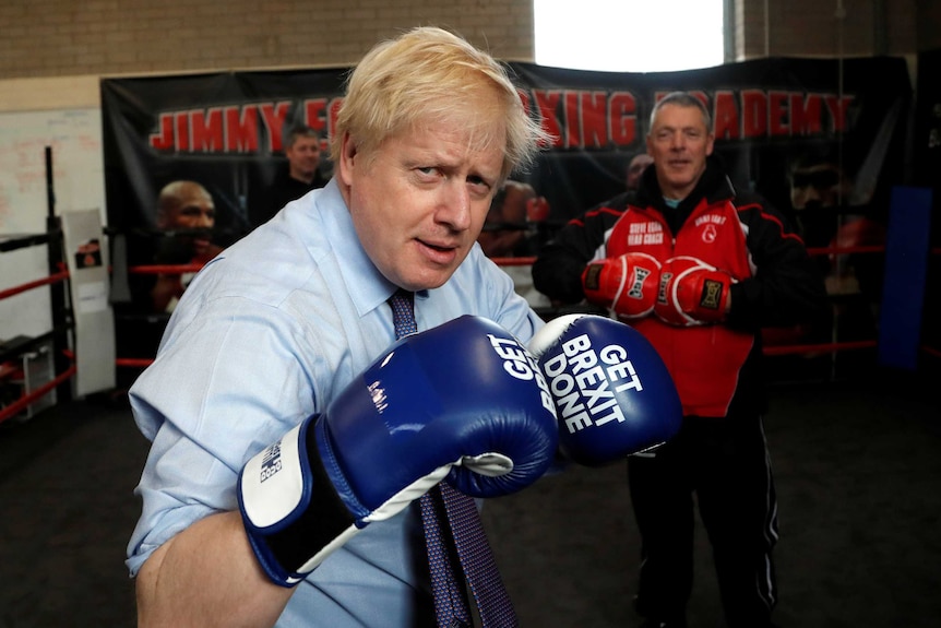 Boris Johnson is pictured in a dimly-lit boxing ring wearing boxing gloves with the words Get Brexit done.
