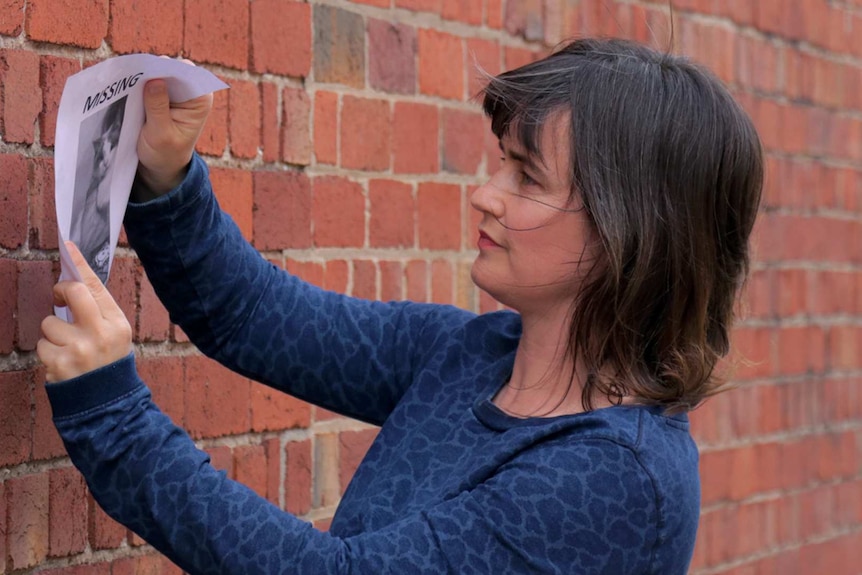 Writer Lorin Clarke fixes a home-printed missing cat poster to a neighbourhood wall.