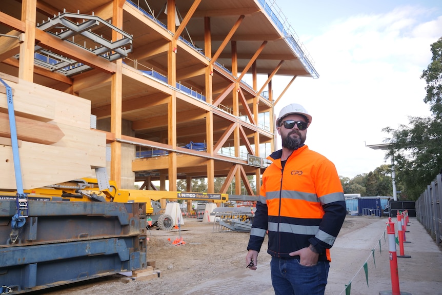 un homme dans un casque se tient à l'extérieur d'un grand bâtiment en bois