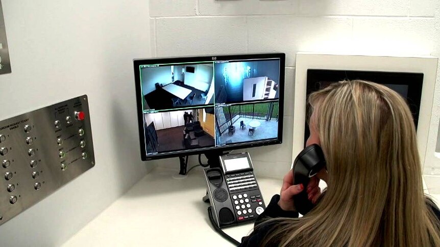 A woman watches a monitor inside a youth detention facility.