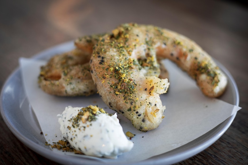 Pumpkin in a sour dough batter and saltbush dukkah with macadamias and fermented pumpkin powder on a plate.