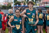 A  young woman and man in football uniforms smile at the camera