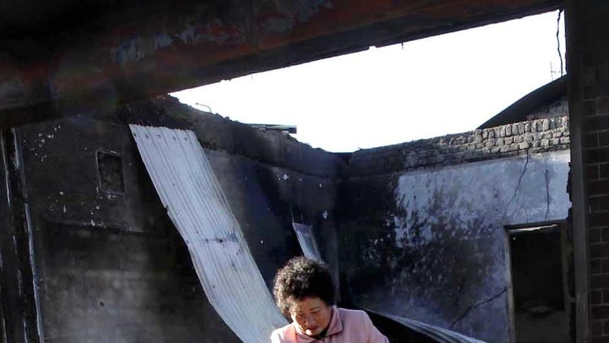 A South Korean resident pulls a bicycle through the wreckage of houses destroyed by artillery shelling.