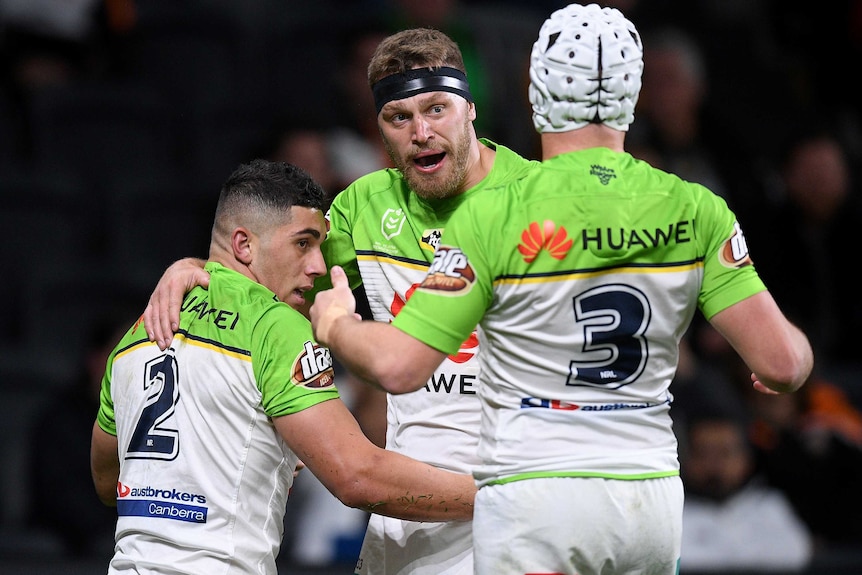 Three NRL teammates celebrate a try.