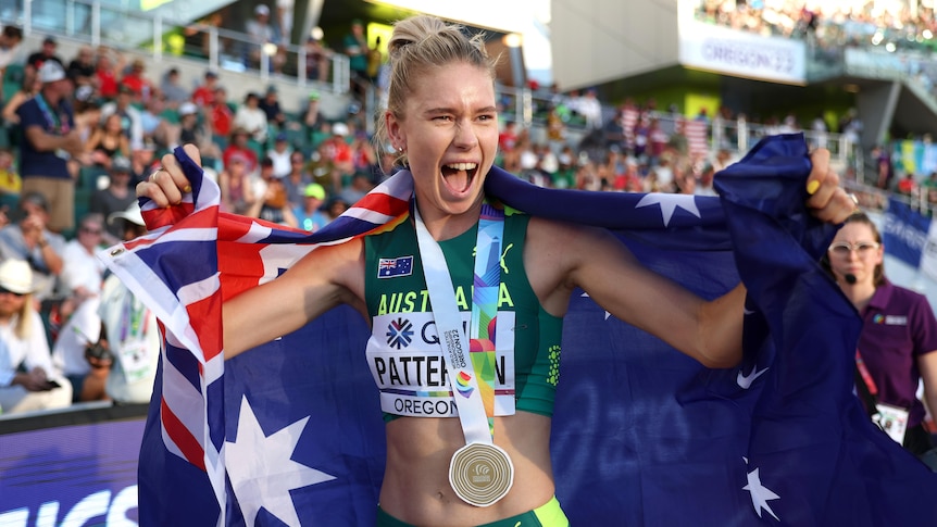 Eleanor Patterson smiles while wearing a gold medal and draped in an Australian flag at the athletics world championships.