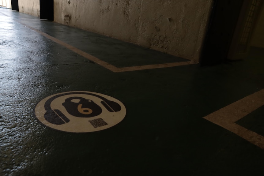 An audio tour marker on the floor of a prison