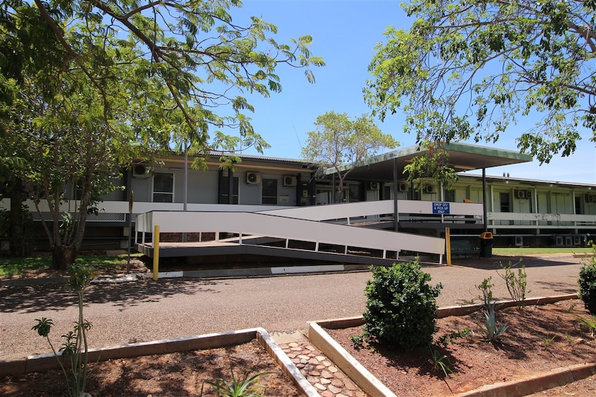 Single story country hospital building behind footpath.