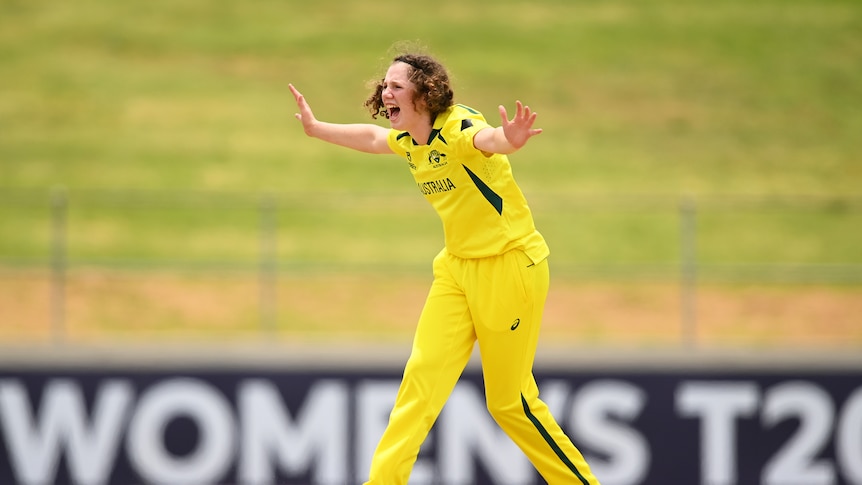 Maggie Clark in her yellow and green Australian cricket uniform turns around and appeals to the umpire on the pitch