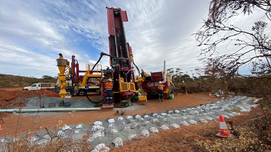 A drill rig being used to extract magnetite from dark red coloured dirt in the outback