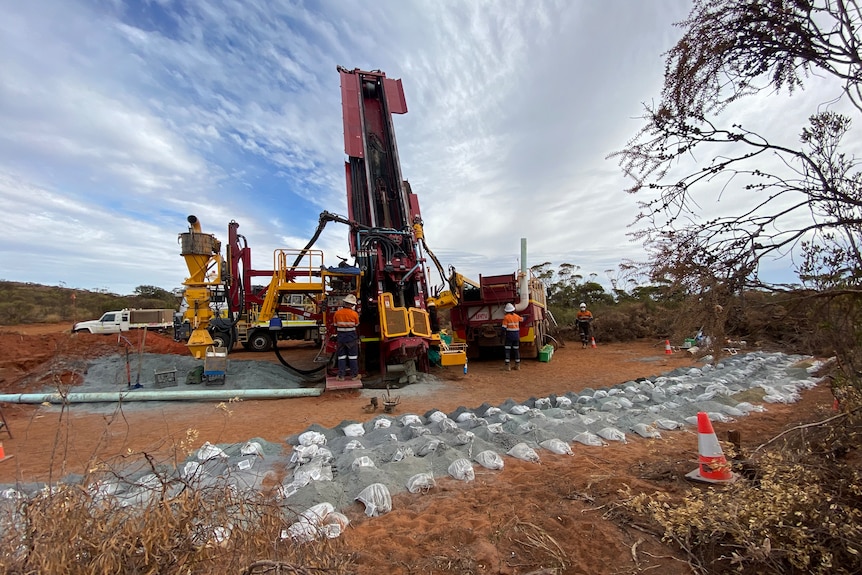 A drill rig being used to extract magnetite from dark red coloured dirt in the outback