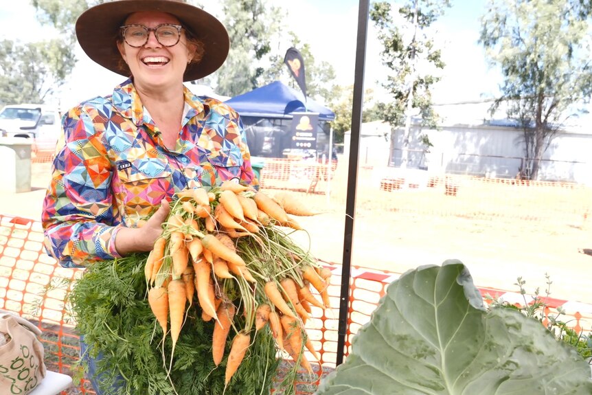 Therese Palmer holds up a massive bunch of carrots pulled from her garden