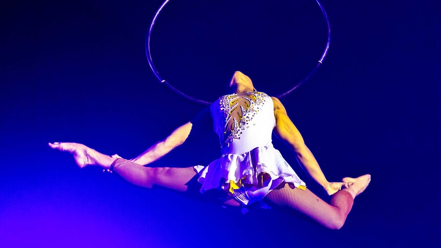 Gabby Souza hangs by her neck on an aerial hoop hanging in the air