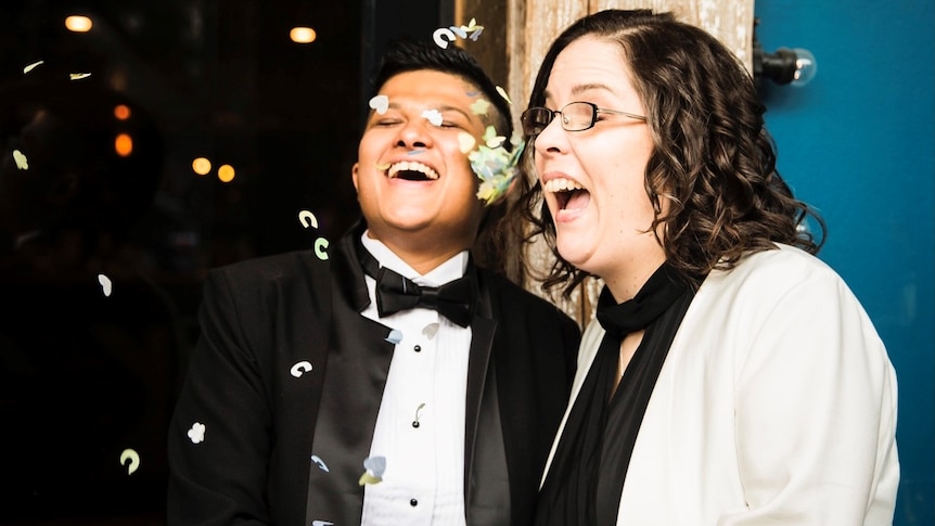 Two women surrounded by confetti, both wearing suits.