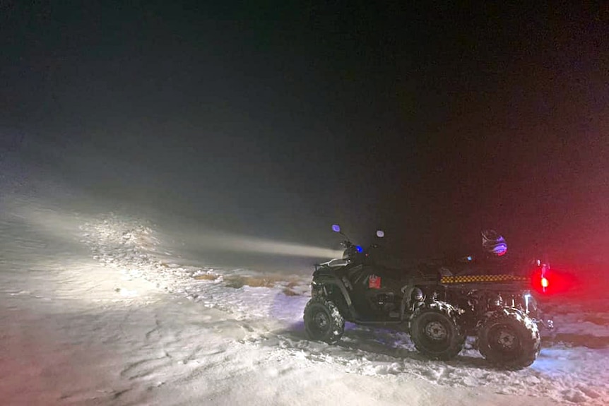 A snowmobile with its lights glowing in the dark.