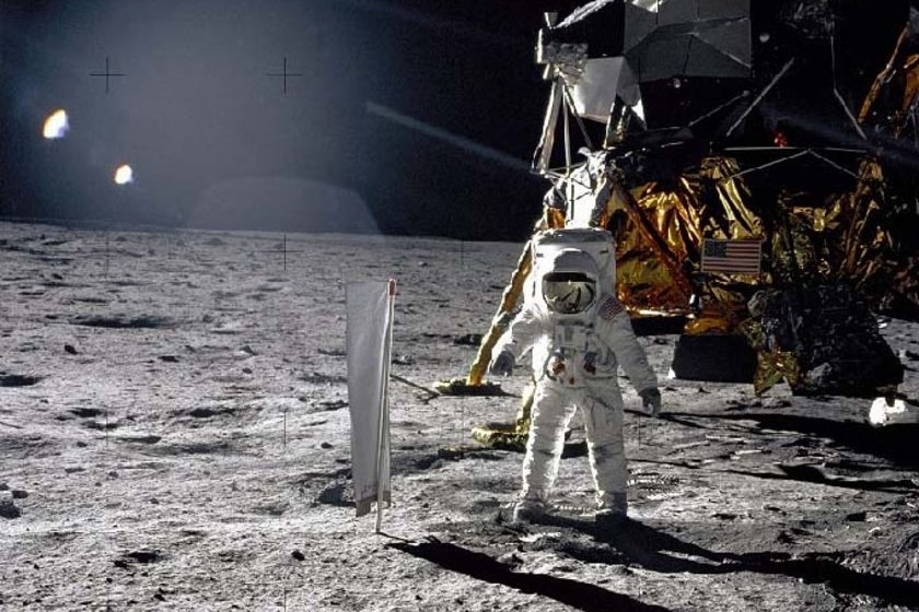 Lunar module pilot Buzz Aldrin unfurls a long sheet of foil on the moon in front of Apollo 11's lunar module, the Eagle.