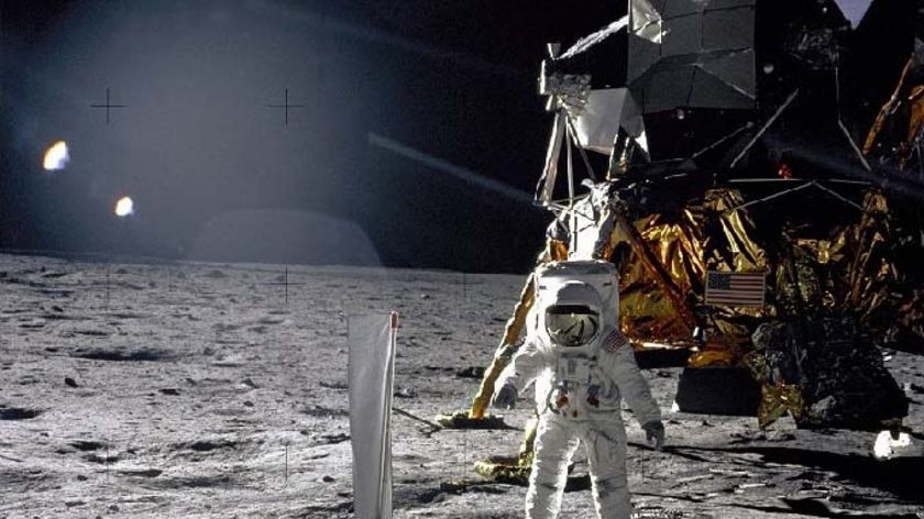 Bright sunlight glints and long dark shadows dramatize this image of the Moon surface. Pictured is the mission's lunar module, the Eagle, and spacesuited lunar module pilot Buzz Aldrin unfurling long sheet of foil also known as the Solar Wind Collector