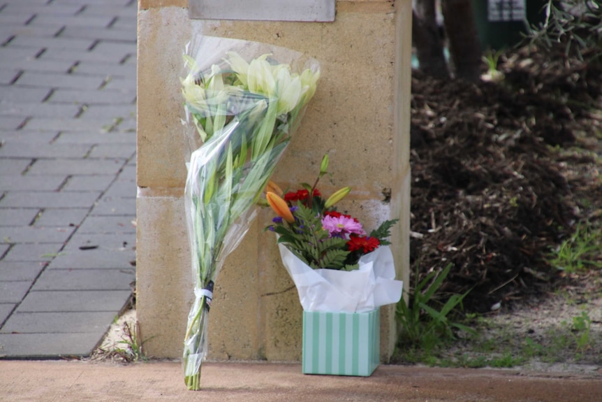 Two bunches of flowers left in front of a cement letterbox