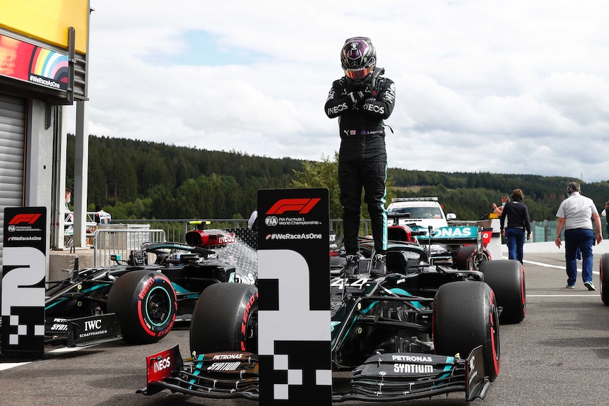 Lewis Hamilton of Britain stands on his car in full gear with his arms crossed over his chest