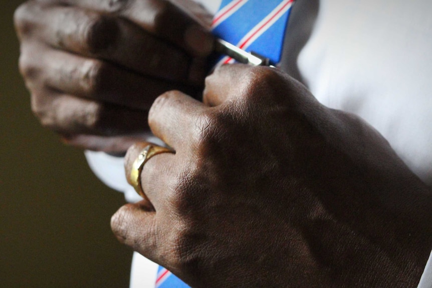 Man adjusting silver tie clip on his tie