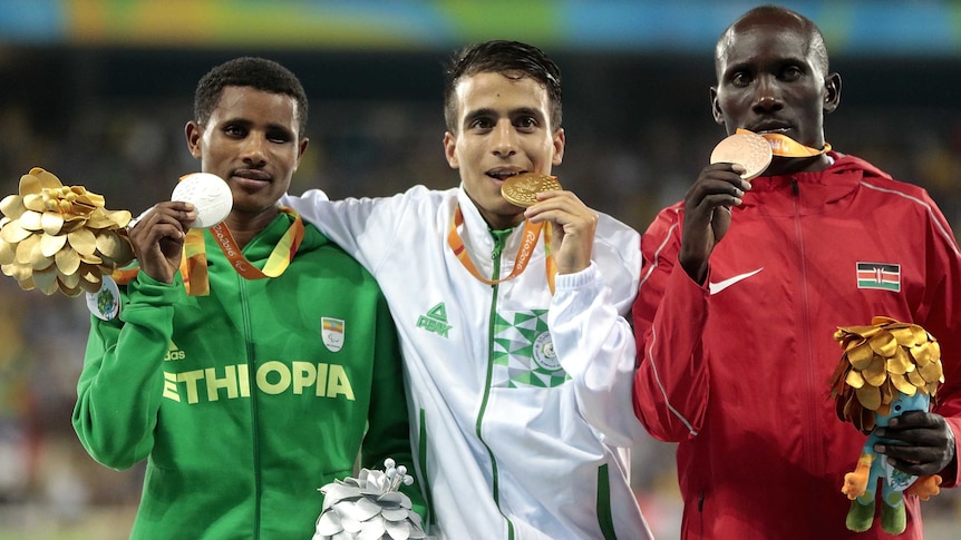 Three medalists stand on the podium after receiving their Olympic medals