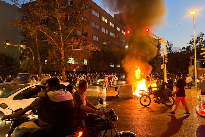 A police motorcycle burns in the street during a protest over the death of Mahsa Amini.