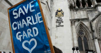 Protester hold 'Save Charlie Gard' placard in front of The Royal Courts of Justice sign