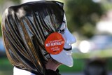 A pro-net neutrality Internet activist wears a mask with a "I support net neutrality" sitcker