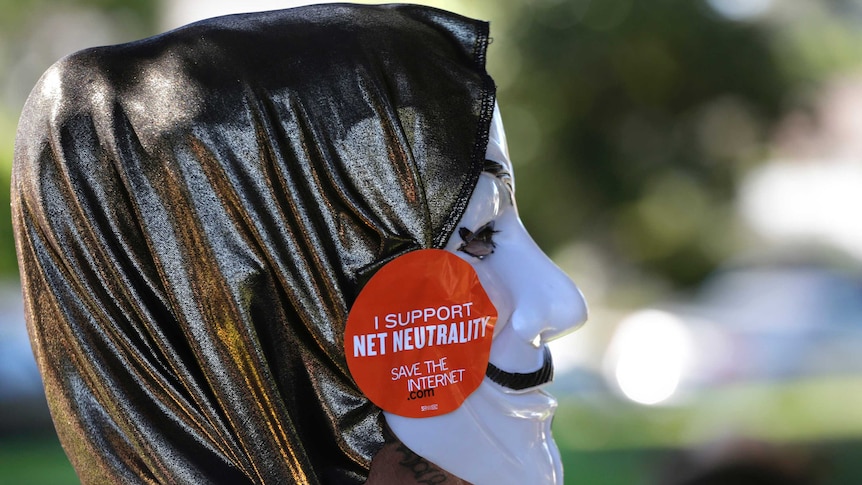 A pro-net neutrality Internet activist wears a mask with a "I support net neutrality" sitcker