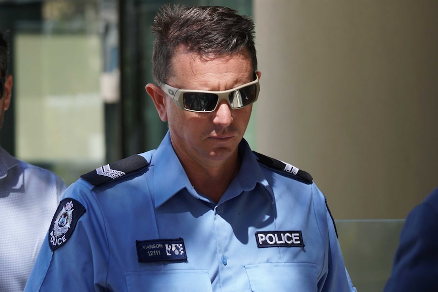 A mid shot of WA Police Senior Constable Joel Vanson walking outside court wearing his uniform and sunglasses.