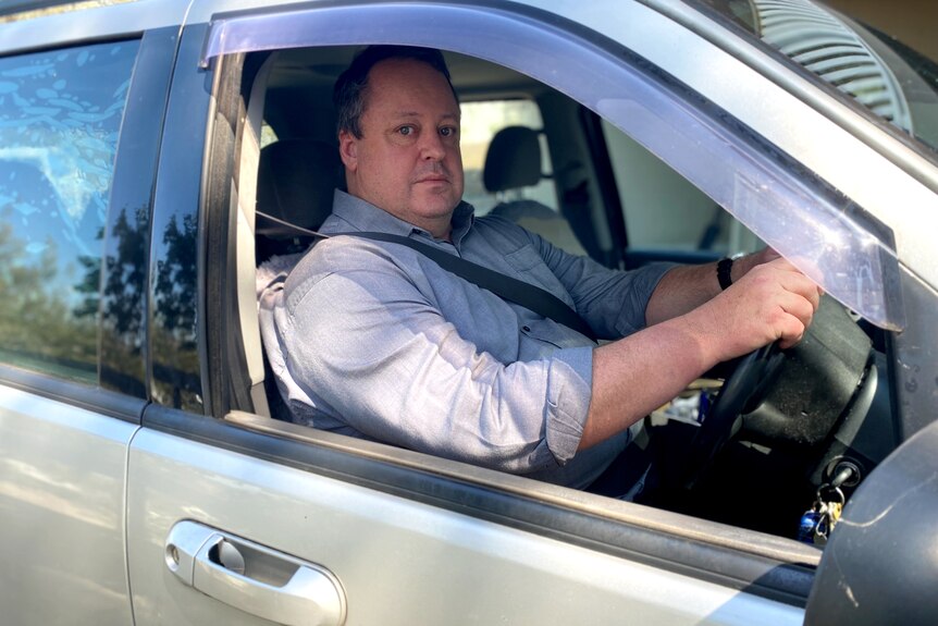Man sits behind the steering wheel of a car