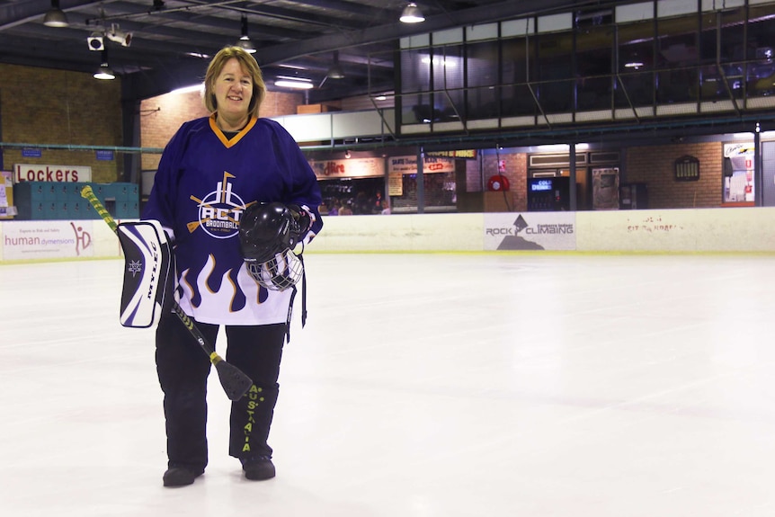 Bridget Whisker stands on the ice with her broomball equipment.