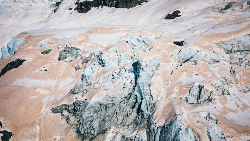 The ice on a glacier is tinged red.