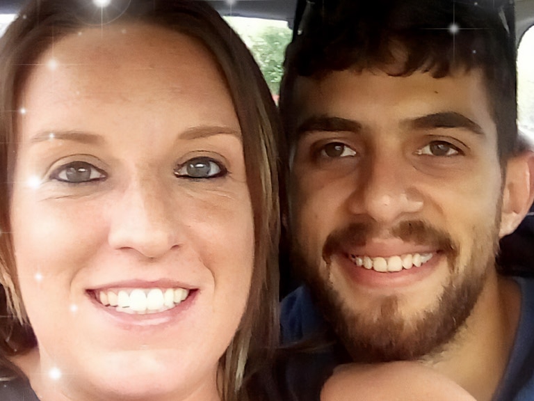 A young woman and a man smile for a selfie while sitting in a car.