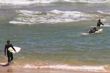 Surfers and swimmers in the water at a beach on Victoria's Mornington Peninsula.