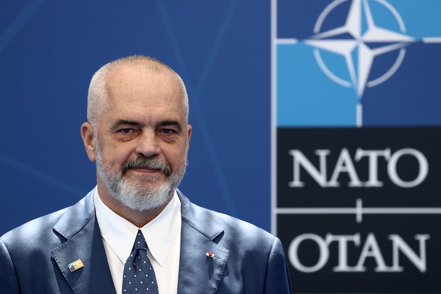 Edi Rama portrait with a NATO logo in the background. 