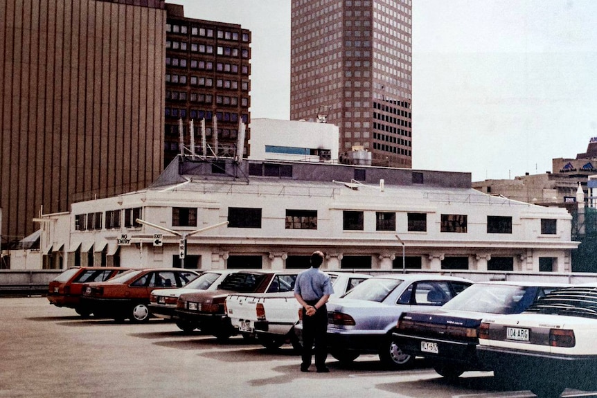 A person looks towards the NCA building from a nearby rooftop.