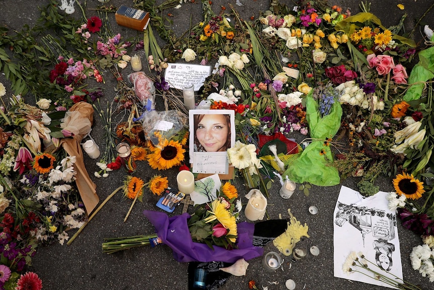 Flowers, candle and cards left on the road, encircle a photo of Heather Heyer.