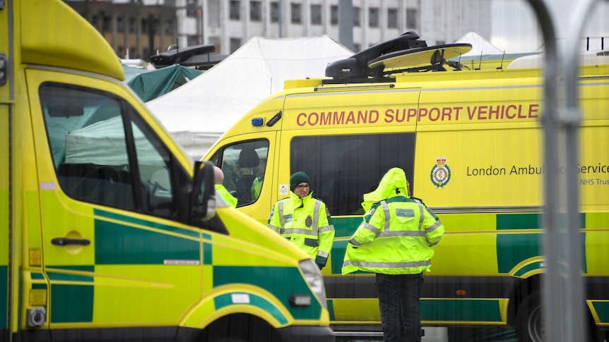 Bright yellow ambulances sit outside a London hospital.