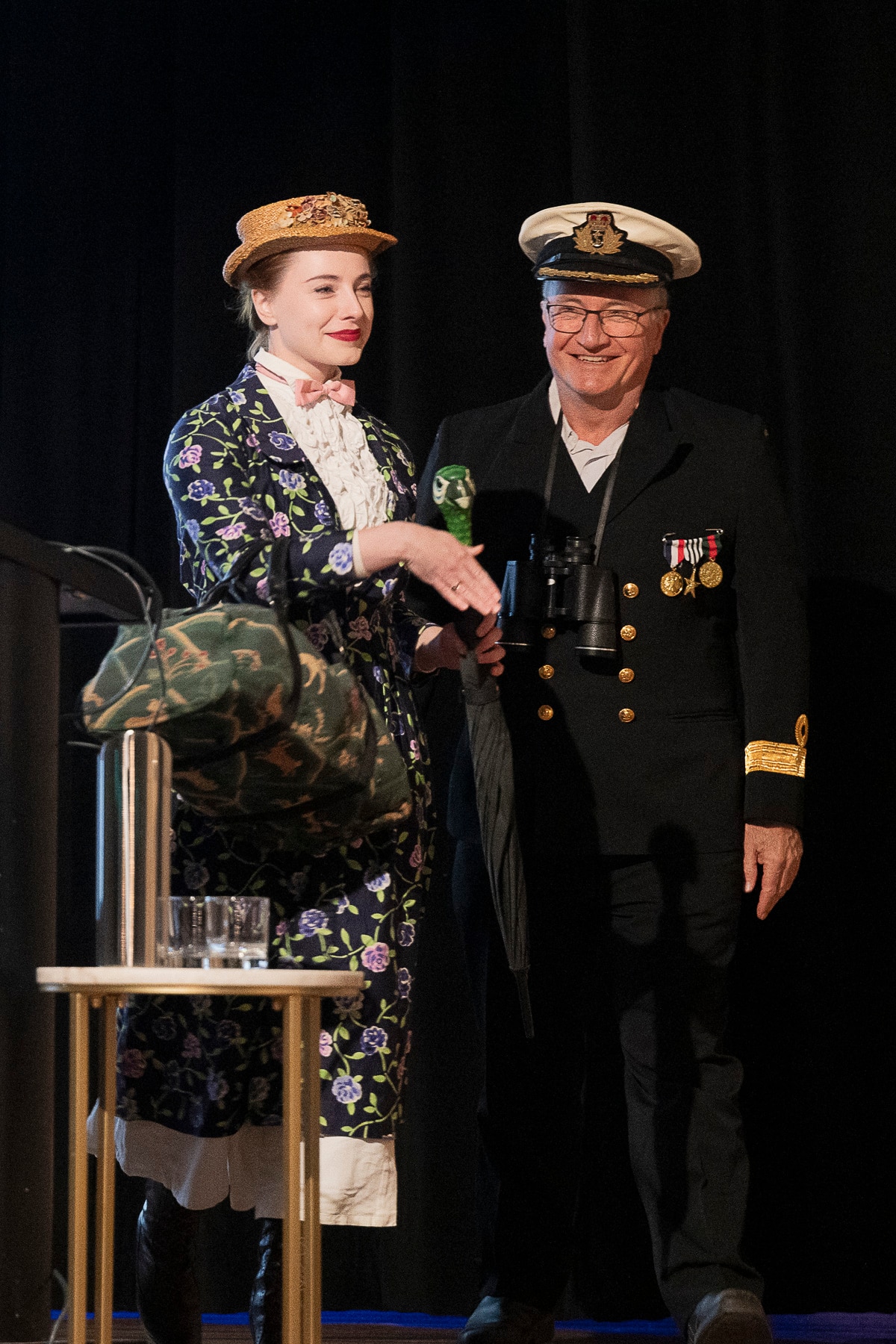 A young woman dressed as Mary Poppins stands with an older man wearing a naval uniform.